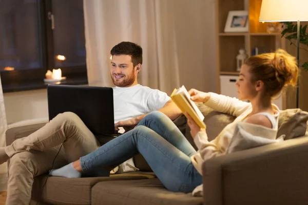 Casal com computador portátil e livro em casa — Fotografia de Stock