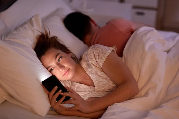 Vrouw met behulp van smartphone terwijl vriendje is slapen — Stockfoto