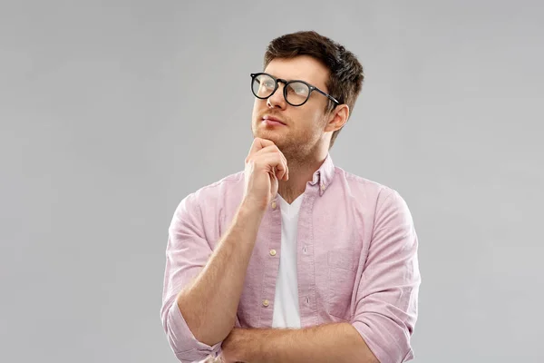 Joven pensante en gafas sobre fondo gris — Foto de Stock