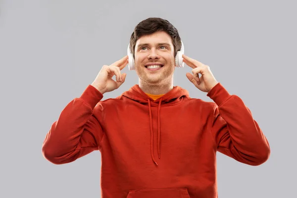 Glücklicher junger Mann mit Kopfhörern und rotem Kapuzenpullover — Stockfoto