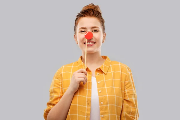 Smiling red haired teenage girl with clown nose — Stock Photo, Image