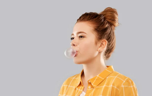 Red haired teenage girl blowing bubble gum — Stock Photo, Image