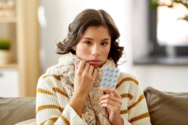 Sick woman in scarf with medicine pills at home — Stock Photo, Image