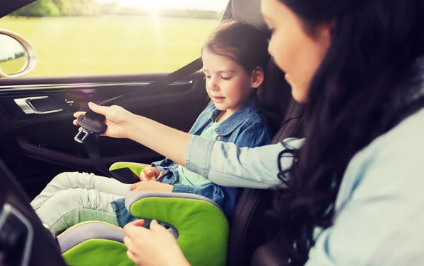 Gelukkige vrouw bevestiging kind met het dragen van de veiligheidsgordel in auto — Stockfoto