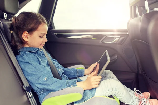 Счастливая маленькая девочка с планшетным компьютером за рулем автомобиля — стоковое фото