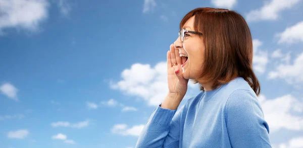 Mujer mayor en gafas llamando por el cielo — Foto de Stock