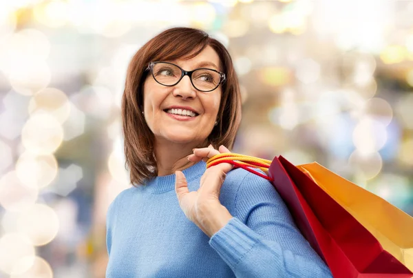 Mulher sênior com sacos de compras sobre cinza — Fotografia de Stock