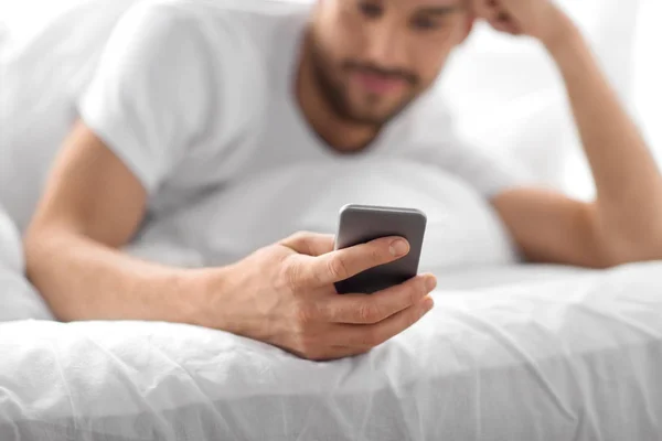 Primer plano del hombre con teléfono inteligente en la cama por la mañana —  Fotos de Stock