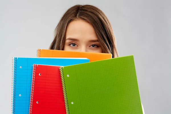 Adolescente estudante menina escondendo atrás de cadernos — Fotografia de Stock
