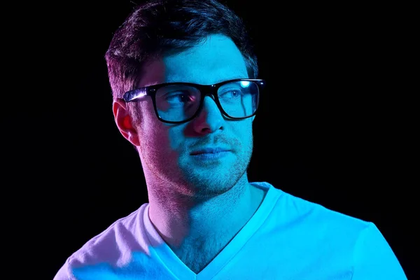 Man in glasses over neon lights in dark room — Stock Photo, Image