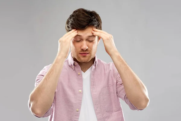 Несчастный молодой человек страдает от головной боли — стоковое фото