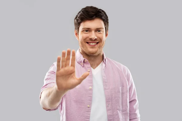 Lächelnder junger Mann zeigt seine Handfläche — Stockfoto