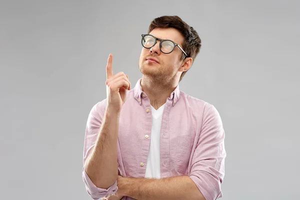 Молодой человек в очках, указывающий пальцем вверх — стоковое фото