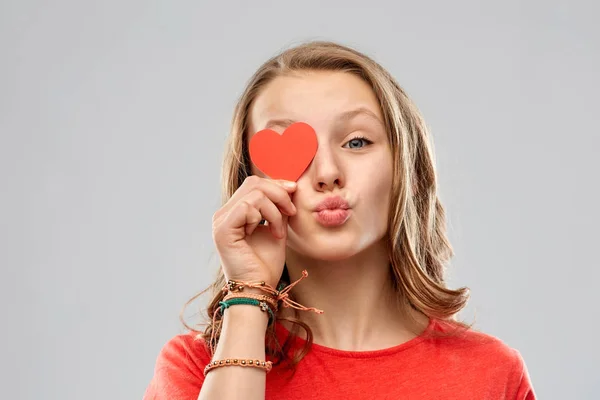 Tonårig flicka som täcker ögat med rött hjärta — Stockfoto