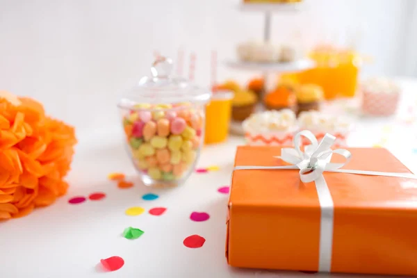 Regalo de cumpleaños en envoltura naranja en la mesa en la fiesta — Foto de Stock