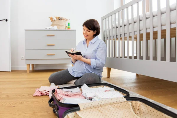 Pregnant woman packing bag for maternity hospital — Stock Photo, Image