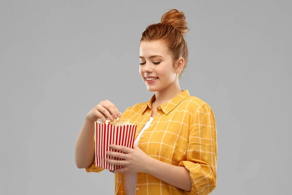 Lachende red haired tienermeisje eten popcorn — Stockfoto
