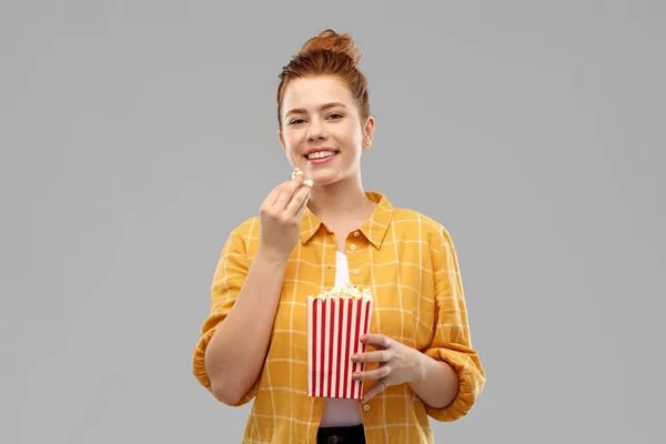 Lächelnde rothaarige Teenagerin, die Popcorn isst — Stockfoto