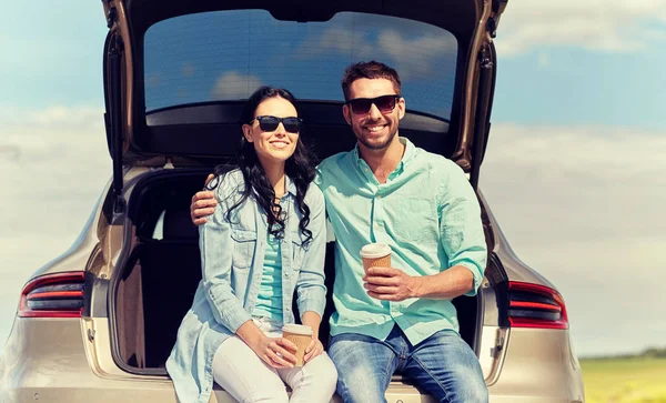 Šťastný pár s kávou v kufru auta hatchback — Stock fotografie