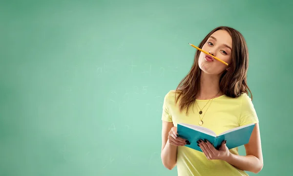 Estudante menina com livro e lápis sobre verde — Fotografia de Stock
