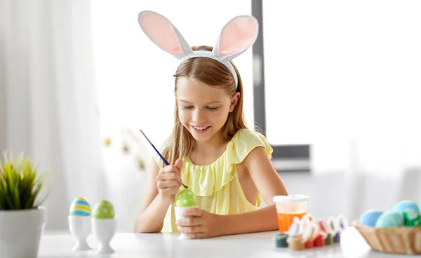 Menina feliz colorir ovos de Páscoa em casa — Fotografia de Stock
