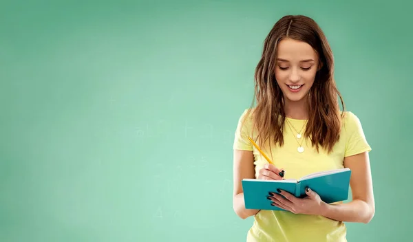 Estudiante escribiendo a cuaderno sobre verde —  Fotos de Stock