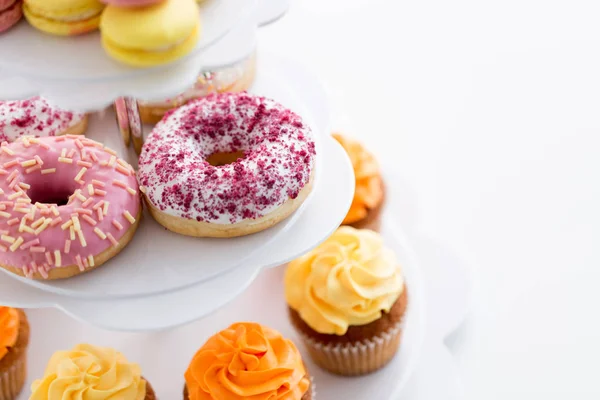 Primer plano de rosquillas vidriadas y cupcakes en stand — Foto de Stock