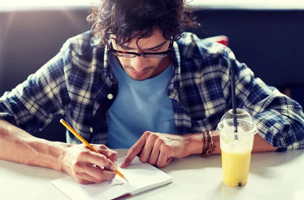 Muž s Poznámkový blok a šťáva psaní v kavárně — Stock fotografie