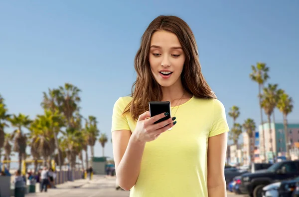 Gadis remaja menggunakan smartphone melalui pantai venice — Stok Foto