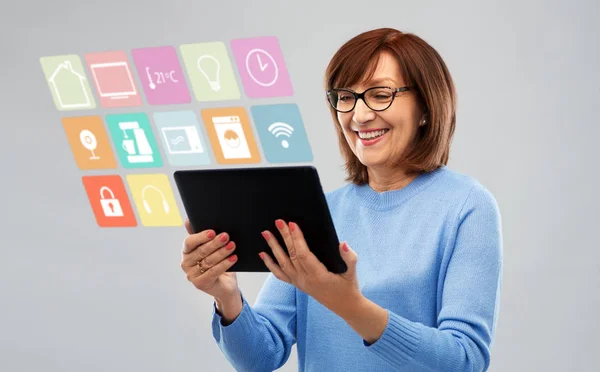 Mujer mayor con PC tableta utilizando la aplicación para el hogar inteligente —  Fotos de Stock