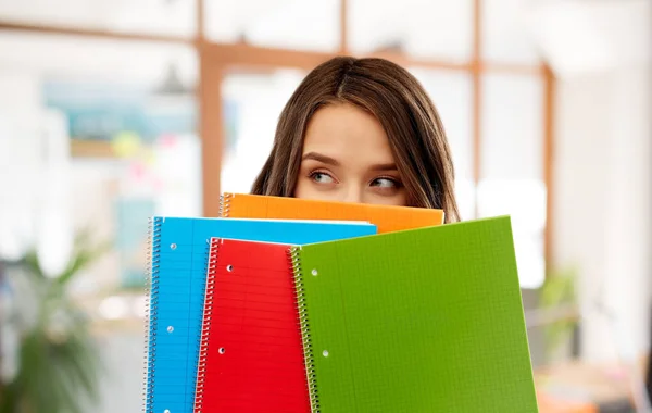 Adolescente estudante menina escondendo atrás de cadernos — Fotografia de Stock