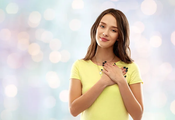 Smiling teenage girl holding hands on heart — Stock Photo, Image