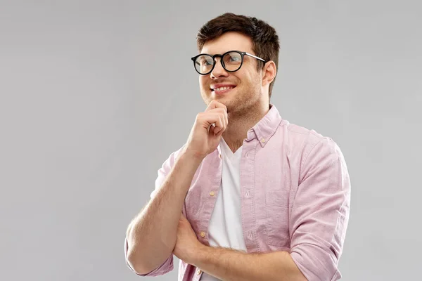 Sorridente giovane uomo in occhiali su sfondo grigio — Foto Stock