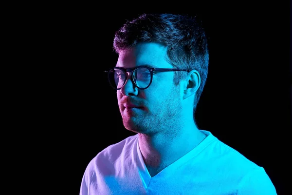 Uomo in occhiali sopra luci al neon in camera oscura — Foto Stock
