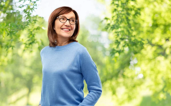 Hogere vrouw in glazen over natuurlijke achtergrond — Stockfoto