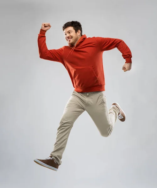 Joven con capucha saltando sobre fondo gris —  Fotos de Stock