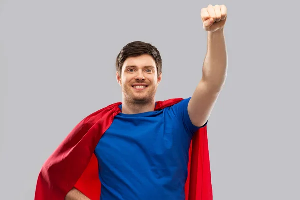 Muž v červených superhrdina cape šedé pozadí — Stock fotografie