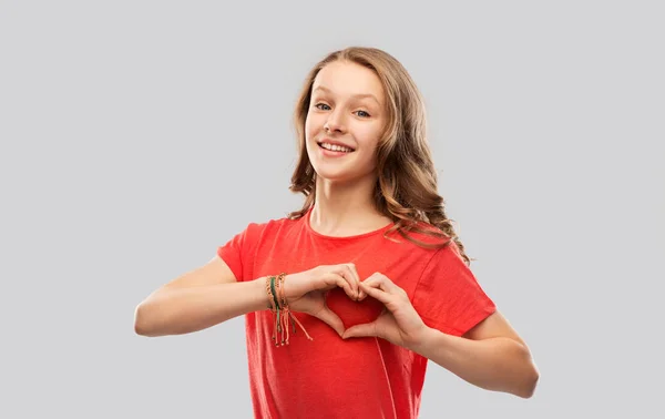 Smiling teenage girl in red making hand heart — Stock Photo, Image