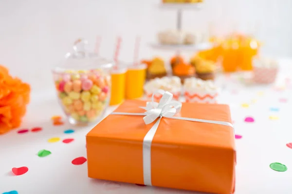 Regalo de cumpleaños en envoltura naranja en la mesa en la fiesta Imagen de stock