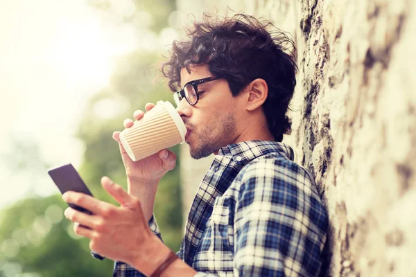 Man with smartphone drinking coffee on city street — Stock Photo, Image