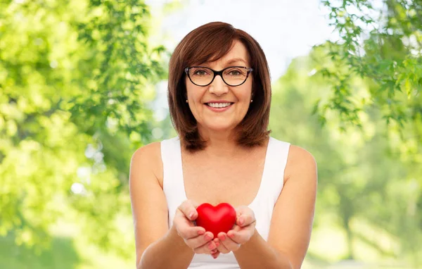 Ritratto di donna anziana sorridente che tiene il cuore rosso — Foto Stock