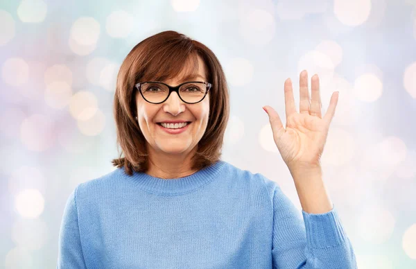 Portrait de femme âgée en lunettes agitant la main — Photo