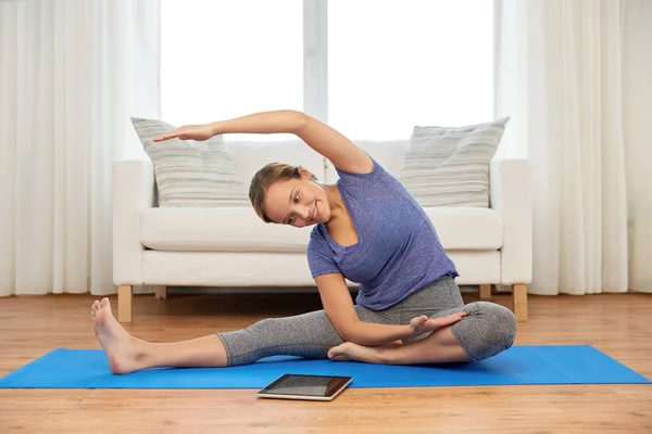 Donna con tablet che fa yoga a casa — Foto Stock