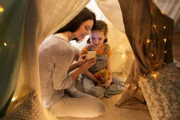 Familia feliz con smartphone en tienda de campaña para niños en casa — Foto de Stock