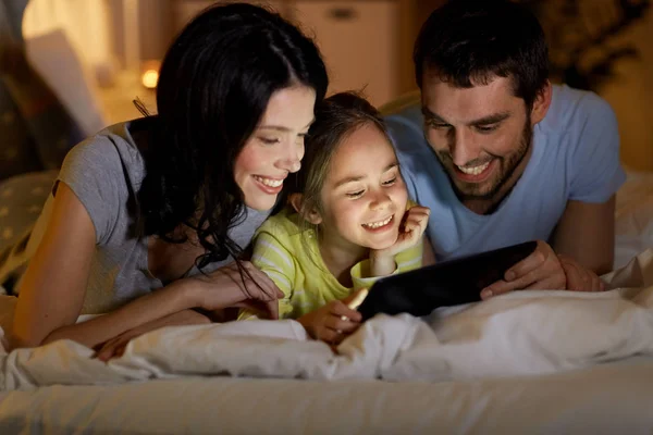 Familia con tableta pc en la cama por la noche en casa — Foto de Stock
