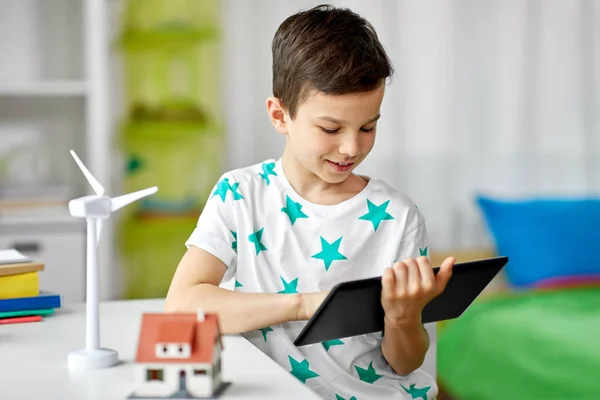 Menino com tablet, casa de brinquedo e turbina eólica — Fotografia de Stock