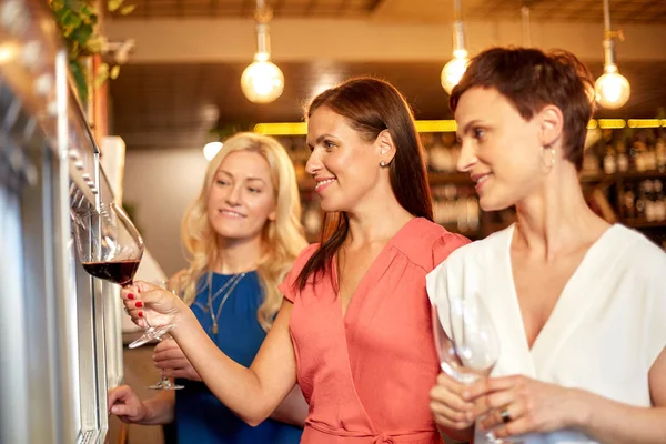 Femmes heureuses versant du vin du distributeur au bar — Photo