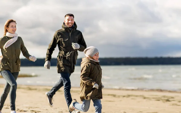 Gelukkige familie loopt langs herfst strand — Stockfoto
