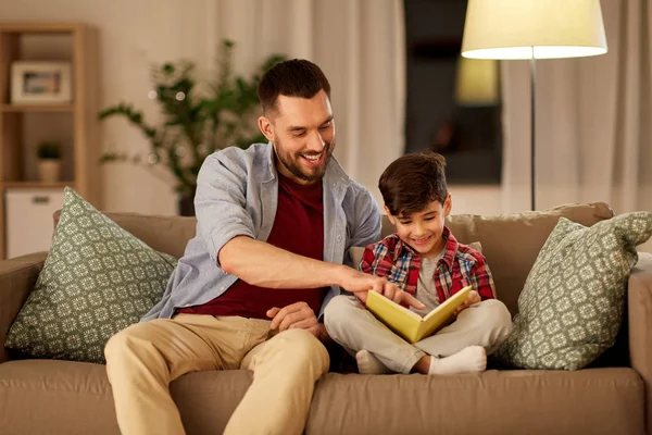 Heureux père et fils lecture canapé livre à la maison — Photo