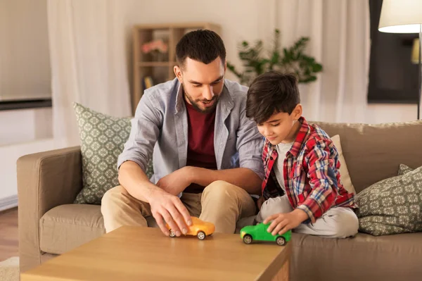 father and son playing with toy cars at home